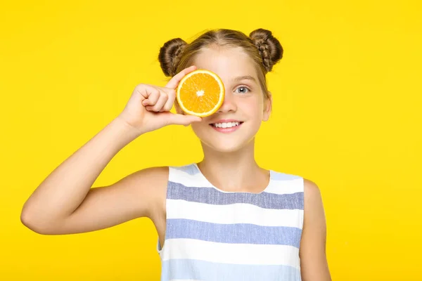 Gadis muda dengan buah oranye dengan latar belakang kuning — Stok Foto