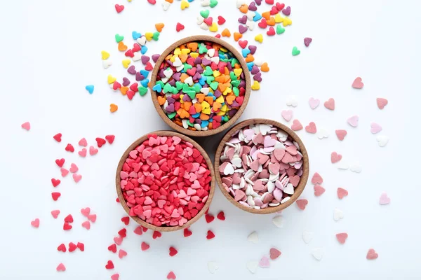 Coloridos espolvoreos en forma de corazón en cuencos sobre fondo blanco — Foto de Stock