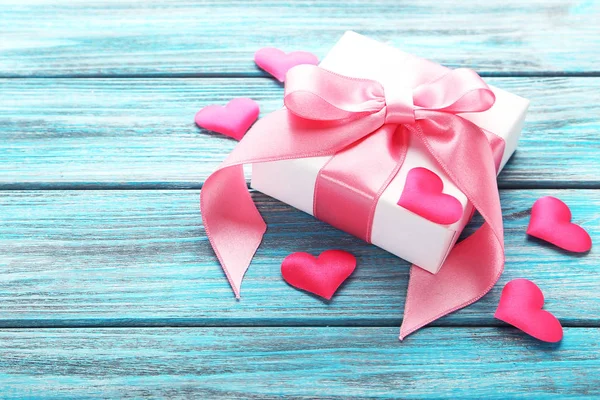 Caja de regalo con cinta y corazones en mesa de madera azul — Foto de Stock