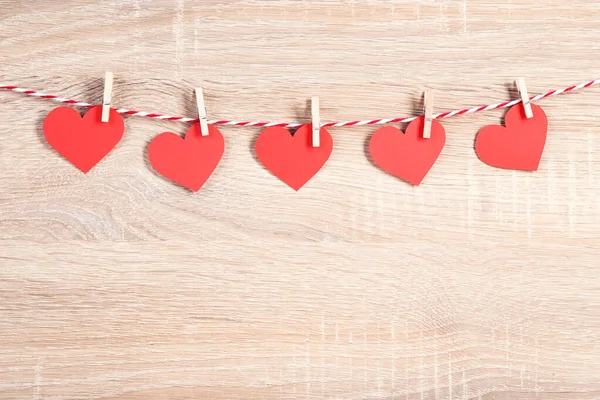Corazón de papel rojo colgando sobre fondo de madera marrón — Foto de Stock
