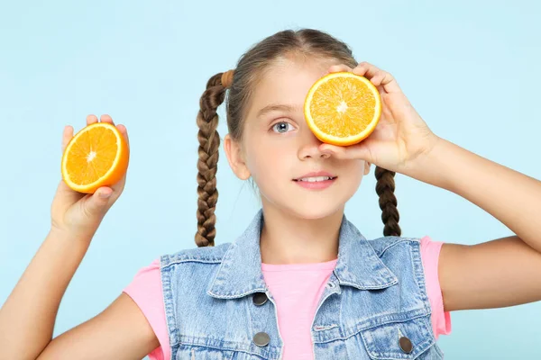 Menina com fruta laranja no fundo azul — Fotografia de Stock