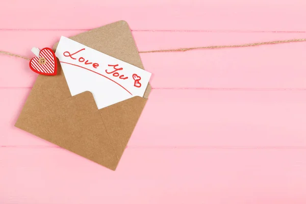 Χάρτινος φάκελος με κείμενο Love You κρέμονται σε ροζ ξύλινο backgro — Φωτογραφία Αρχείου