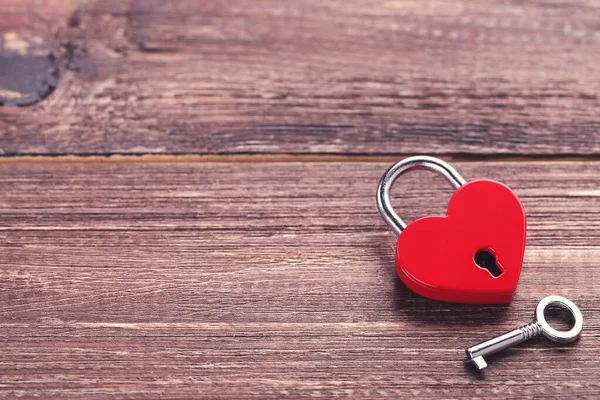 Valentine heart shaped padlock with key on brown wooden table — Stock Photo, Image