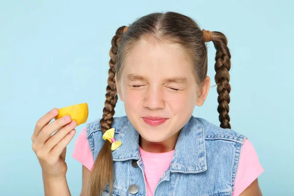Gadis muda makan buah lemon di latar belakang biru — Stok Foto