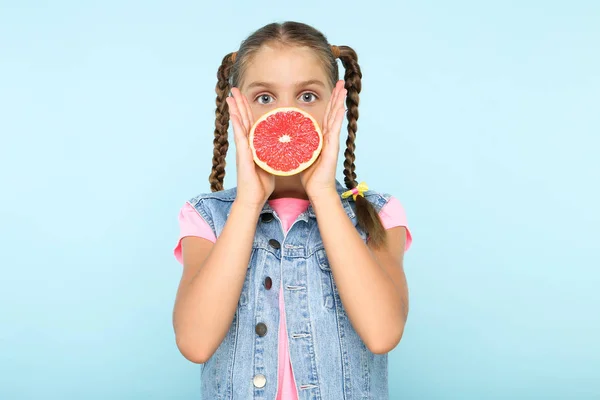 Gadis muda dengan jeruk di latar belakang biru — Stok Foto