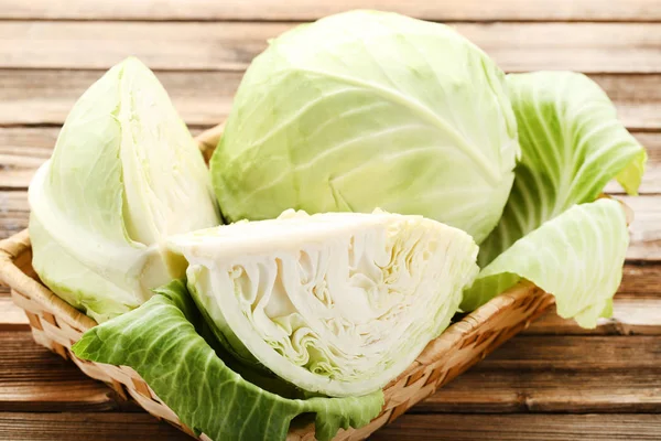 Ripe cabbage in basket on brown wooden table — 스톡 사진