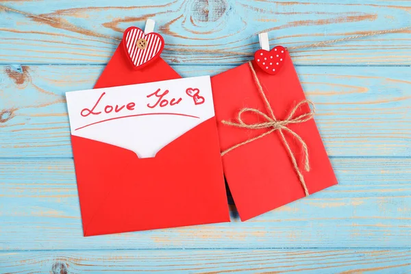 Κόκκινο χαρτί φακέλους με καρδιές και κείμενο Αγάπη Μπορείτε κρέμονται σε blu — Φωτογραφία Αρχείου