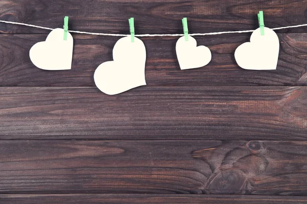 Білі паперові серця висять на коричневому дерев'яному фоні — стокове фото
