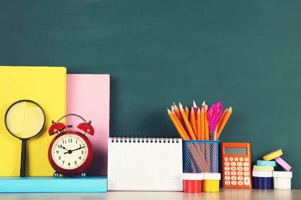 Material escolar con despertador rojo sobre fondo verde —  Fotos de Stock