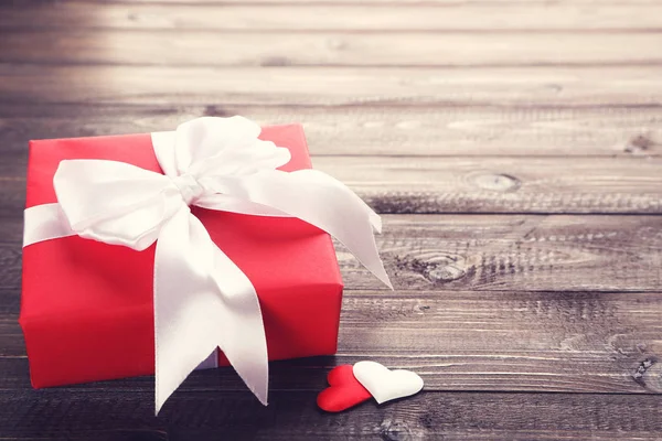 Caja de regalo con cinta y corazones en mesa de madera —  Fotos de Stock