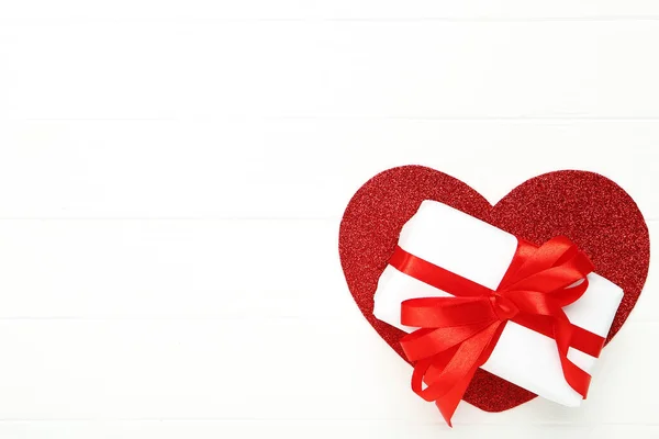 Pudełko z wstążką i czerwonym sercem na białym drewnianym stole — Zdjęcie stockowe