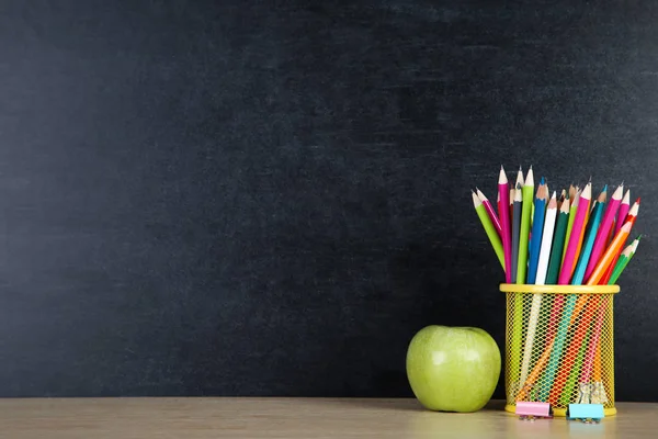 Schulbedarf mit grünem Apfel auf Tafel-Hintergrund — Stockfoto