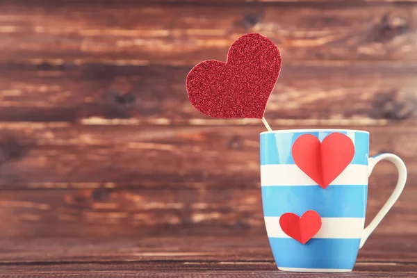 Corazones de papel con taza sobre mesa de madera marrón —  Fotos de Stock