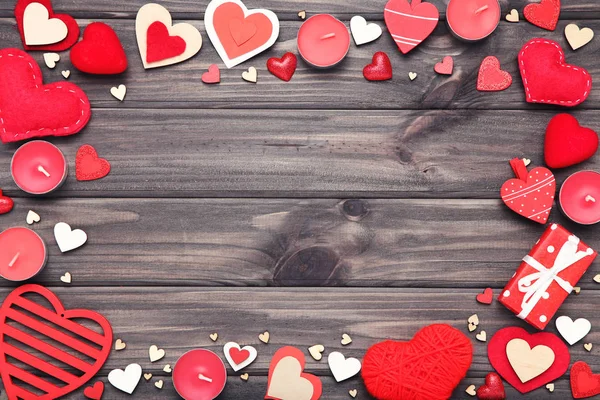 Valentine hearts with gift box and candles on wooden table