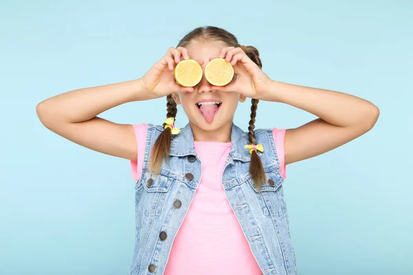 Gadis muda menutupi mata dengan buah lemon di latar belakang biru — Stok Foto