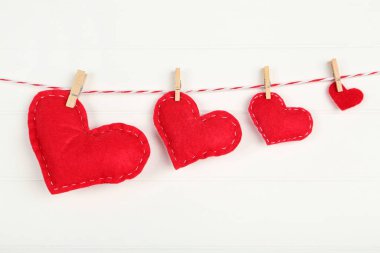 Beyaz ahşap sırtüstü asılı mandallı kumaş kalpler.