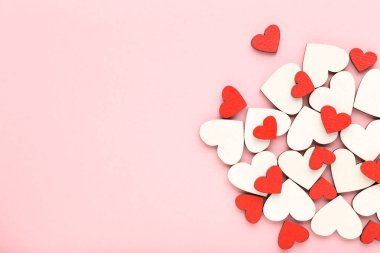 Pembe arka planda tahta beyaz ve kırmızı kalpler.