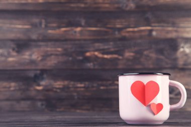 Kahverengi ahşap masada kupalı kağıt kalpler.