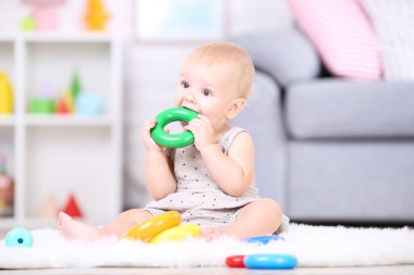 Güzel küçük çocuk oturuyor ve fahişelerde plastik oyuncaklarla oynuyor.