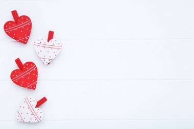 Beyaz ahşap masada mandallı sevgililer günü kalpleri.