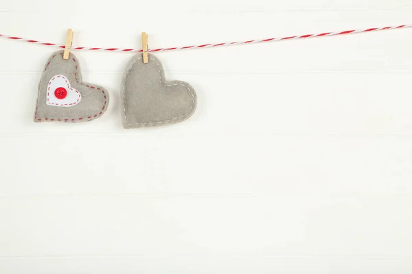 Tyghjärtan med klädnypor hängande på vit trä backgroun — Stockfoto