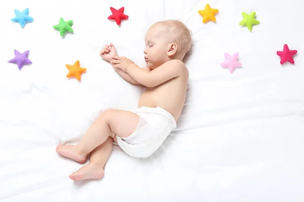 Beautiful little boy sleeping on bed at home with colorful fabri — Stock Photo, Image