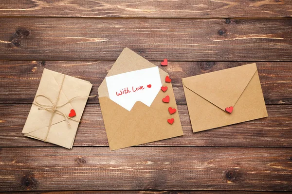 Papierowe koperty z sercami i tekstem Z miłością na brązowym drewnianym t — Zdjęcie stockowe