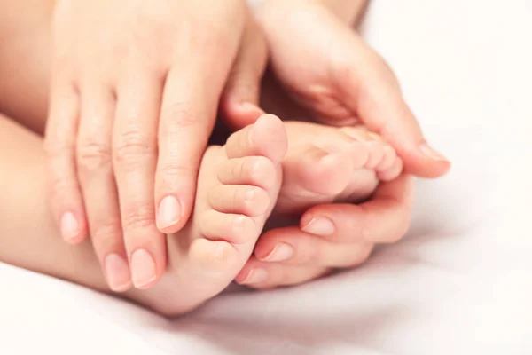 Mor hand hålla hennes barn fötter medan han sover — Stockfoto