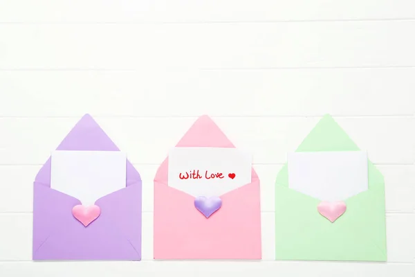 Colorful paper envelopes with hearts and text With Love on white