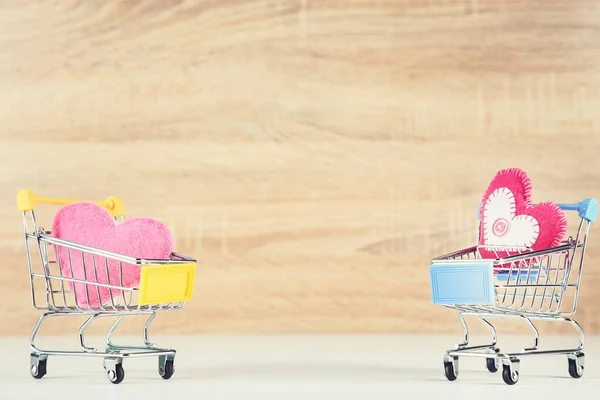 Corazones de tela con carritos de compras sobre fondo de madera — Foto de Stock