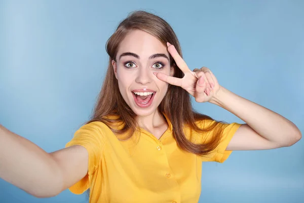 Jong mooi meisje maken selfie op blauw achtergrond — Stockfoto