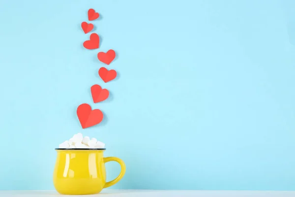 Χάρτινες καρδιές και κίτρινη κούπα με ζαχαρωτά σε μπλε φόντο — Φωτογραφία Αρχείου