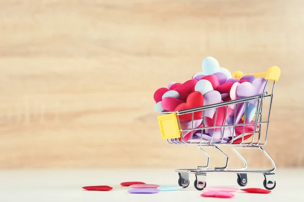 Corazones coloridos con carrito de compras sobre fondo de madera — Foto de Stock