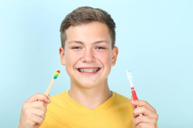 Mavi arka planda diş fırçası olan genç bir adam.