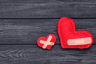 Siyah tahta masada bandajlı kırmızı kumaş kalpler.