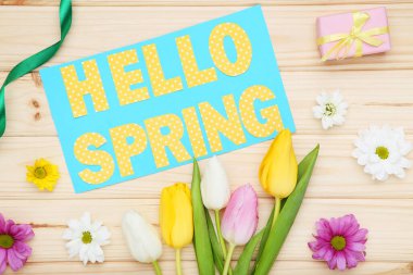 Tulip, kasımpatı çiçekleri ve yazı. Kahverengi ahşap masada bahar.