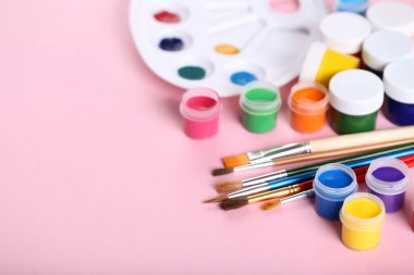 Renkli gouache pembe arka planda boya ve fırçalar