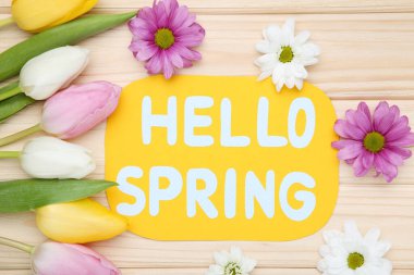 Tulip, kasımpatı çiçekleri ve yazı. Kahverengi ahşap masada bahar.