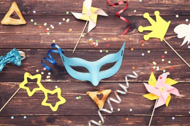 Purim tatil kompozisyonu. Kahverengi ahşap masada parti malzemeleri olan kurabiyeler.