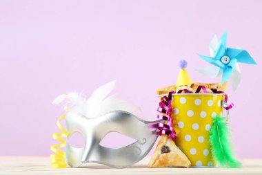 Purim tatil kompozisyonu. Kovalı kurabiyeler ve pembe arka planda malzemeler.