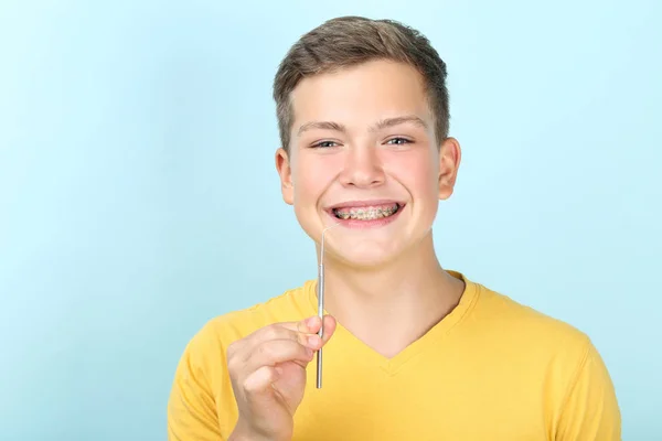 Junger Mann Mit Zahnspange Und Zahnarztwerkzeug Auf Blauem Hintergrund — Stockfoto