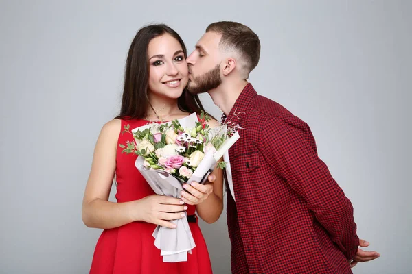 幸せな若いですカップルともに花の花束上灰色の背景 — ストック写真