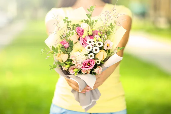 Female hands holding beautiful flower bouquet in the park