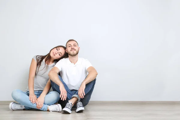 Feliz Joven Pareja Sentada Suelo Sobre Fondo Gris — Foto de Stock