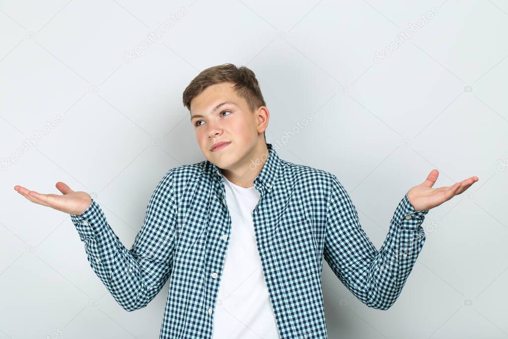 Portrait of young man showing confusion gesture on grey background