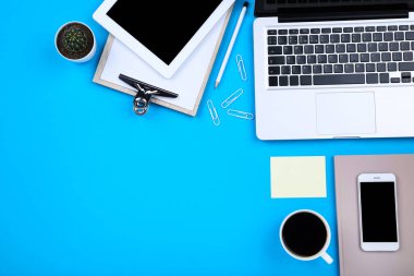 Tablet, akıllı telefonlu dizüstü bilgisayar, kaktüs ve mavi arka planda pano