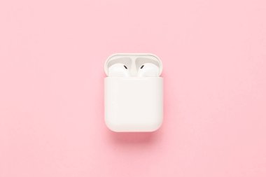 Pembe arka planda beyaz kablosuz kulaklıklar