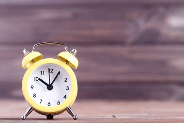 Ahşap masada sarı alarm saati