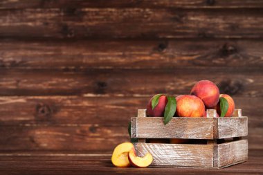 Kahverengi ahşap masa üzerinde sandık yeşil yapraklı taze şeftali