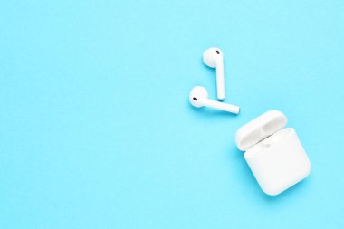 Mavi arka planda beyaz kablosuz kulaklıklar